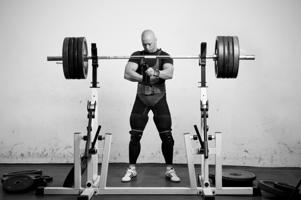Powerlifter with strong arms preparing to lift a heavy dumbbell
