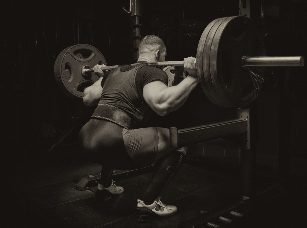 Professional athlete makes squats with a bar